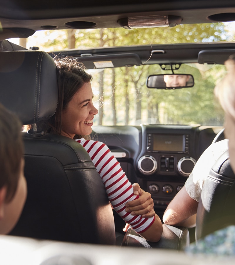Family smiling inside their car while the sunroof is open.
