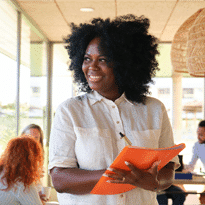 Smiling woman in an office holding a folder.