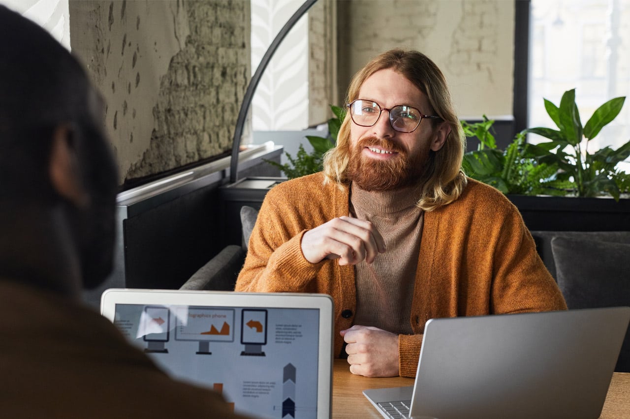 Man talking and collaborating with a coworker at a table.